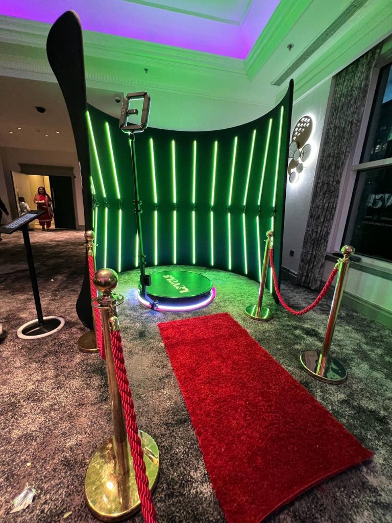 Levels 360 Video Booth — neon backdrop, LED platform, red carpet, and gold stanchions