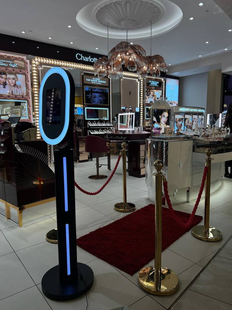 Levels selfie booth with ring light, red carpet, and velvet ropes at a Charlotte Tilbury retail event